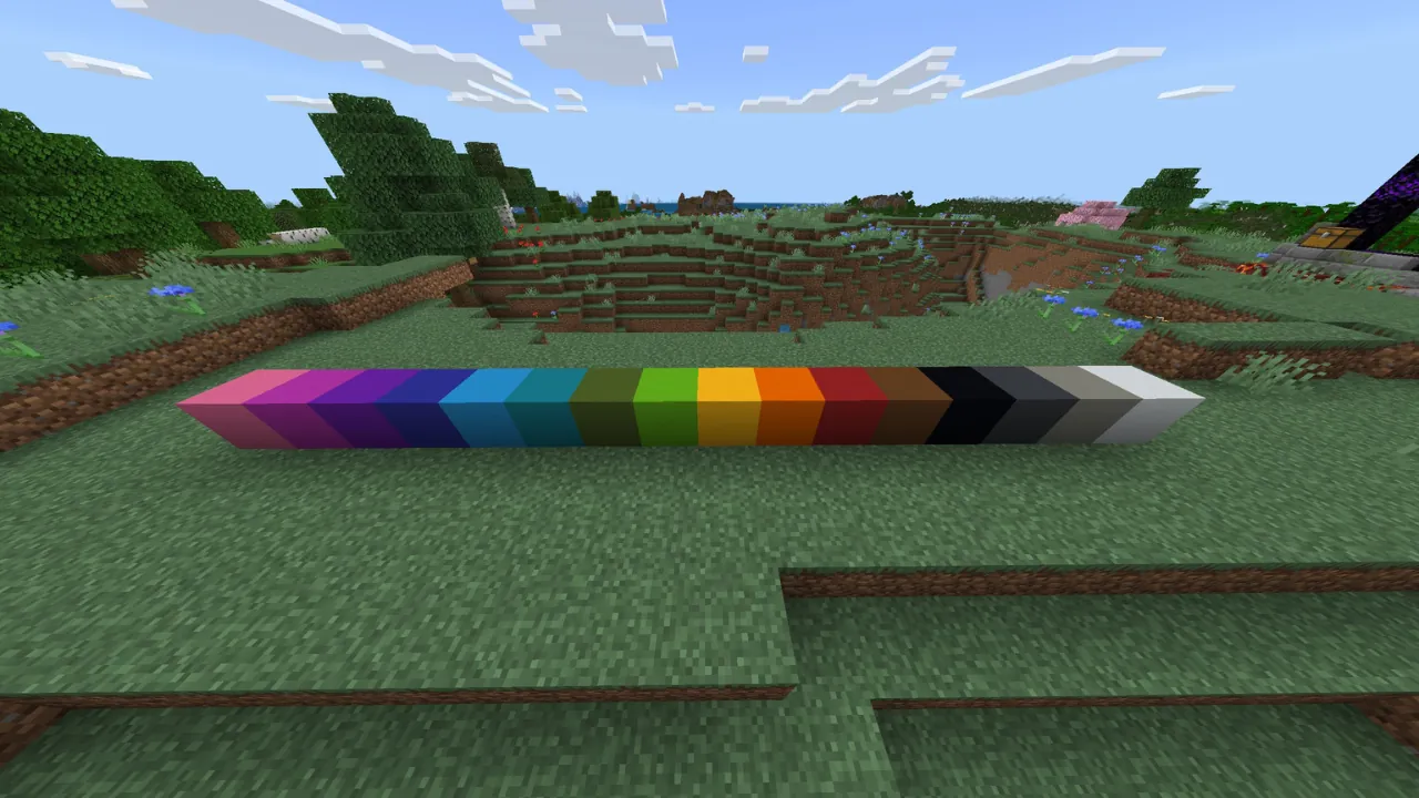 Minecraft screenshot showing a gradient of 16 colored concrete blocks on grass in an overworld biome.