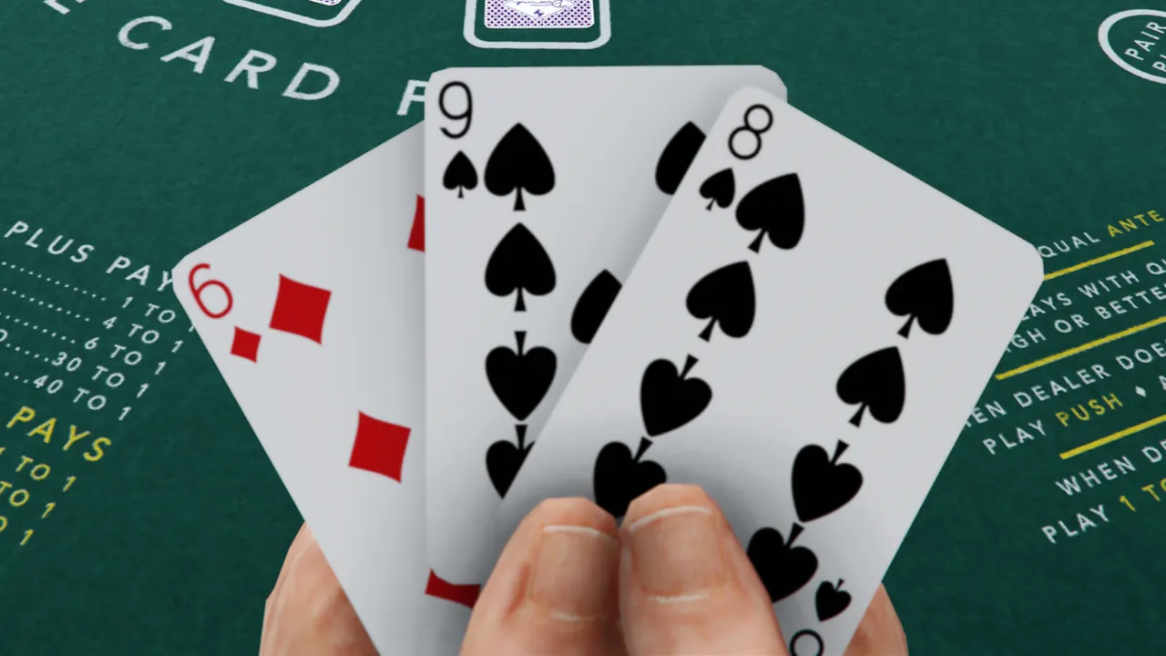 A hand holding three playing cards (6 of Diamonds, 8 of Spades, 9 of Spades) over a green casino table with game rules.