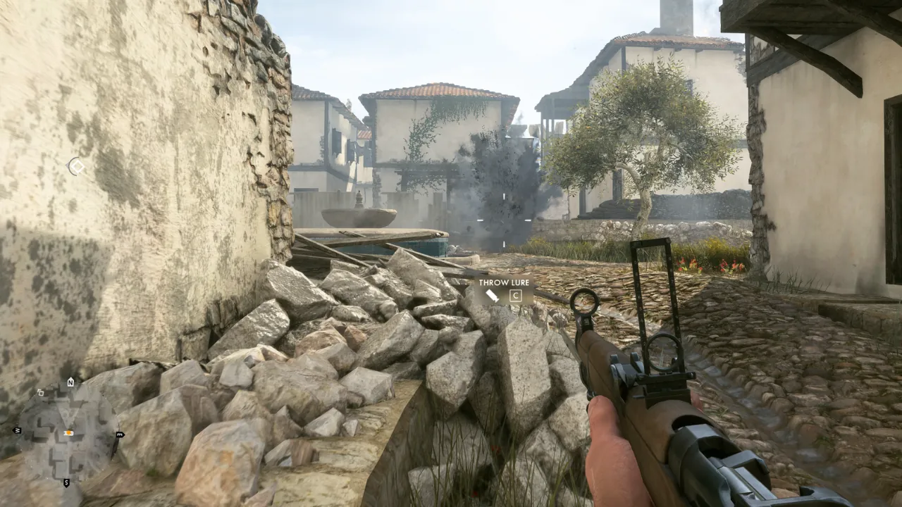 First-person perspective in a video game, showing a player holding a rifle amidst rubble in a war-torn village with explosions.